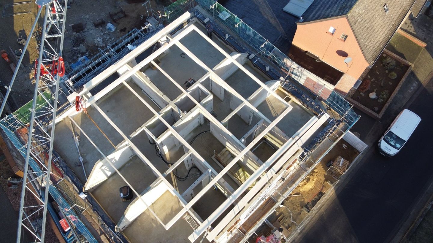 Luftaufnahme einer Rohbaustelle, auf der tragende Wände und Unterzüge von oben ein klares Raster bilden