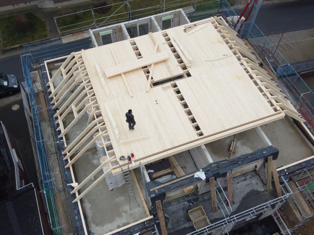 Blick von oben auf eine Holzbalkendecke, die über dem Obergeschoss eines Neubaus verlegt wird